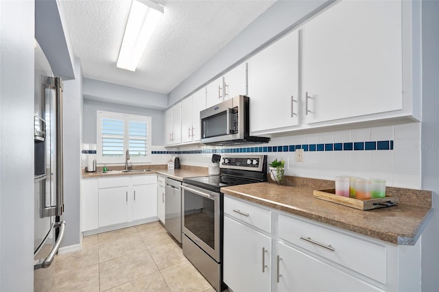 3180 Ocean Shore Blvd Unit 309, Ormond Beach, FL 32176 - kitchen with stainless steel appliances, a sink, a textured ceiling, white cabinetry, and decorative backsplash