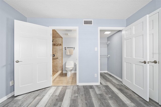 3180 Ocean Shore Blvd Unit 309, Ormond Beach, FL 32176 - unfurnished bedroom with a textured ceiling, wood finished floors, baseboards, a closet, and a walk in closet
