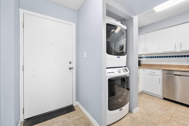 3180 Ocean Shore Blvd Unit 309, Ormond Beach, FL 32176 - washroom featuring stacked washer / dryer, light tile patterned flooring, and baseboards