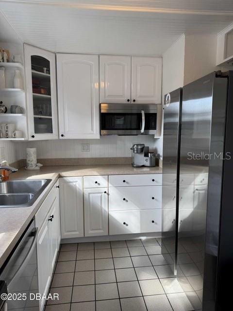 kitchen with sink, tile patterned floors, stainless steel appliances, and white cabinets