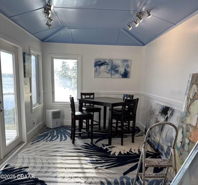 carpeted dining room featuring lofted ceiling and rail lighting