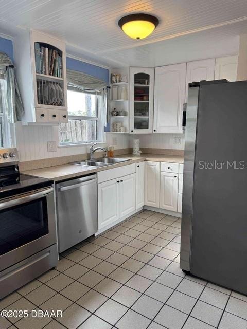 kitchen with sink, light tile patterned floors, stainless steel appliances, and white cabinets