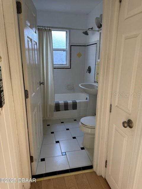 bathroom with tile patterned flooring, shower / bathtub combination with curtain, and toilet