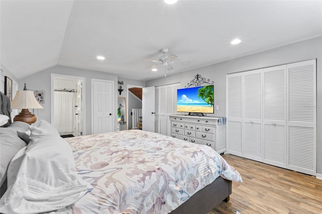 bedroom with multiple closets, ceiling fan, lofted ceiling, and light hardwood / wood-style floors