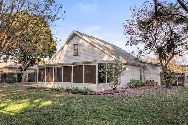 back of house with a sunroom and a lawn