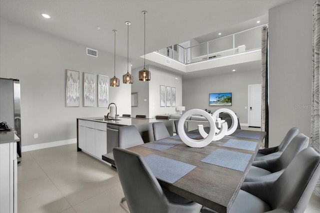 dining area with sink, a towering ceiling, and light tile patterned floors