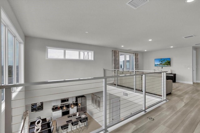 hallway with light hardwood / wood-style floors and a wealth of natural light