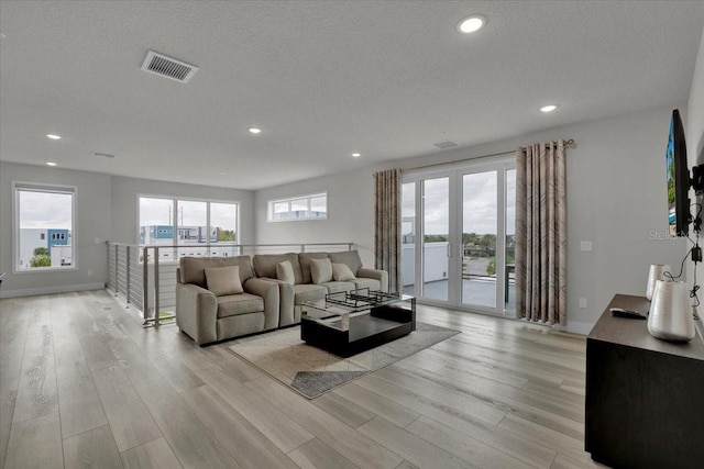 living room featuring french doors, a textured ceiling, and light wood-type flooring