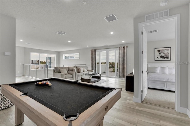 recreation room featuring pool table, light hardwood / wood-style flooring, and a textured ceiling