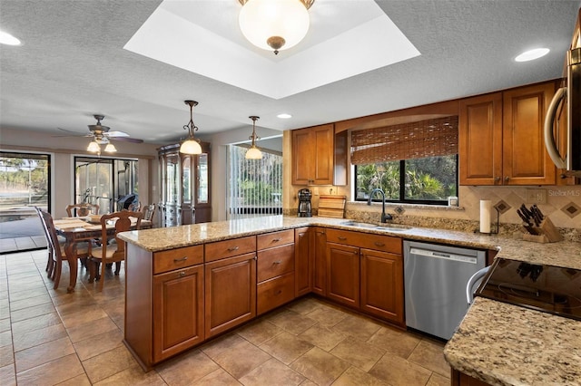 kitchen featuring pendant lighting, sink, kitchen peninsula, stainless steel appliances, and light stone countertops