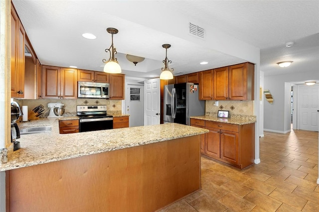 kitchen with light stone countertops, appliances with stainless steel finishes, kitchen peninsula, and hanging light fixtures