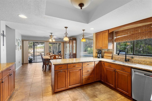 kitchen with sink, dishwasher, kitchen peninsula, pendant lighting, and light stone countertops