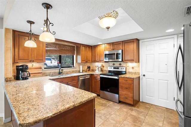 kitchen with sink, hanging light fixtures, appliances with stainless steel finishes, a tray ceiling, and kitchen peninsula