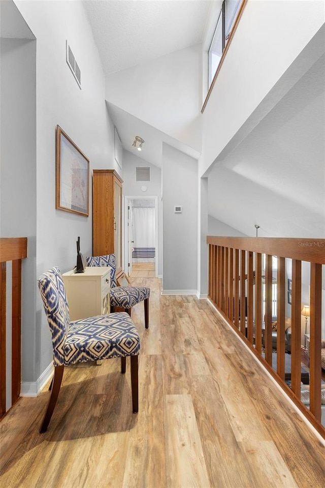 living area with high vaulted ceiling and light hardwood / wood-style floors