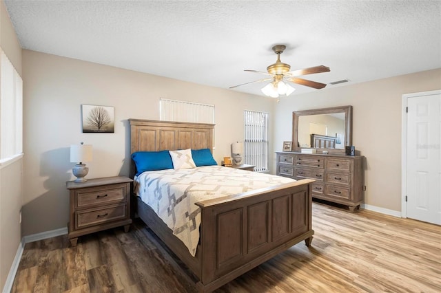 bedroom with ceiling fan, light hardwood / wood-style flooring, and a textured ceiling