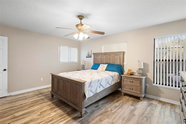 bedroom with ceiling fan, a textured ceiling, and light hardwood / wood-style flooring