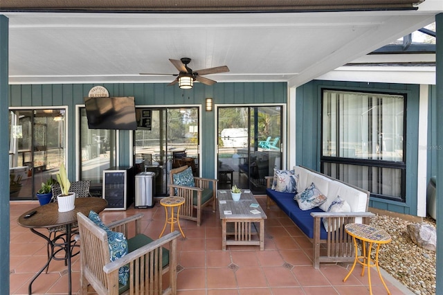 sunroom / solarium with beamed ceiling, plenty of natural light, beverage cooler, and ceiling fan