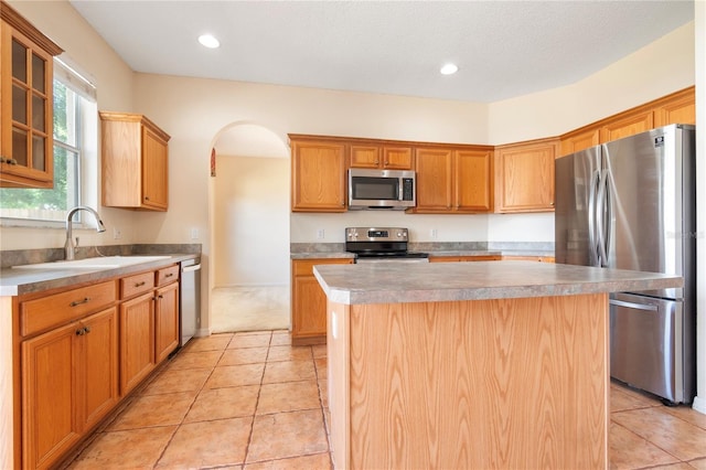 kitchen with sink, light tile patterned flooring, stainless steel appliances, and a kitchen island