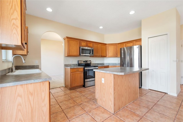 kitchen featuring sink, stainless steel appliances, a center island, and light tile patterned flooring