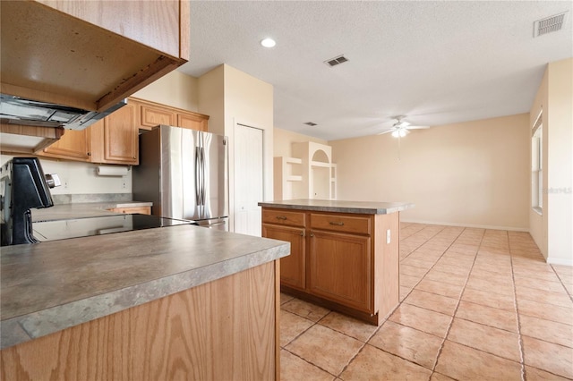 kitchen featuring range, light tile patterned floors, stainless steel fridge, a kitchen island, and ceiling fan