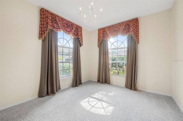 carpeted spare room with a healthy amount of sunlight and a notable chandelier