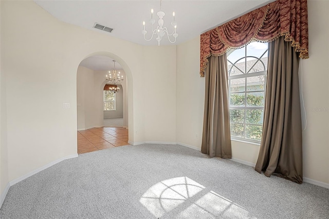 carpeted empty room with an inviting chandelier and a healthy amount of sunlight