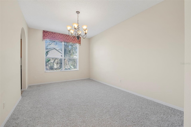 empty room featuring a chandelier, carpet, and a textured ceiling