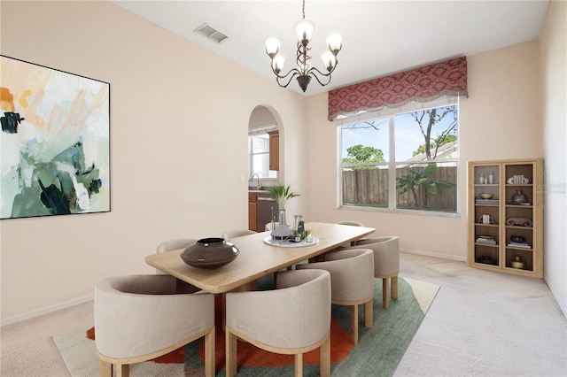 carpeted dining area featuring a chandelier and sink