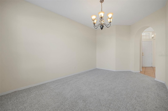 carpeted empty room featuring a chandelier