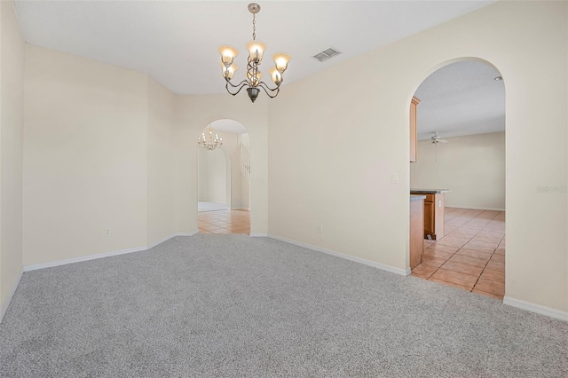 empty room with ceiling fan with notable chandelier and light colored carpet