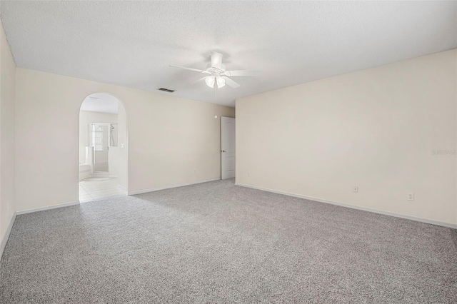 spare room featuring ceiling fan, light colored carpet, and a textured ceiling