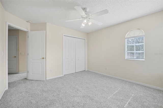 unfurnished bedroom with ceiling fan, light carpet, a textured ceiling, and a closet