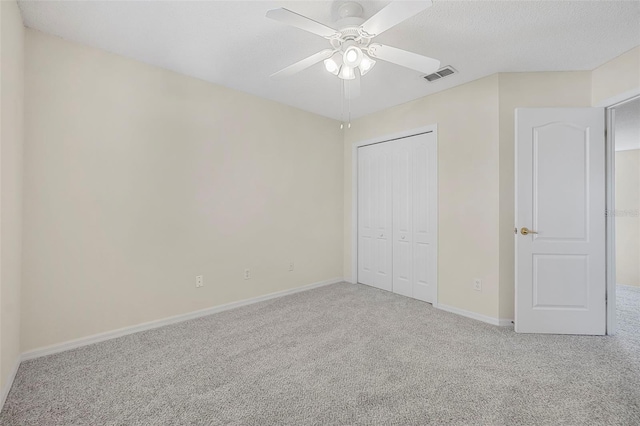 unfurnished bedroom featuring ceiling fan, carpet floors, a closet, and a textured ceiling