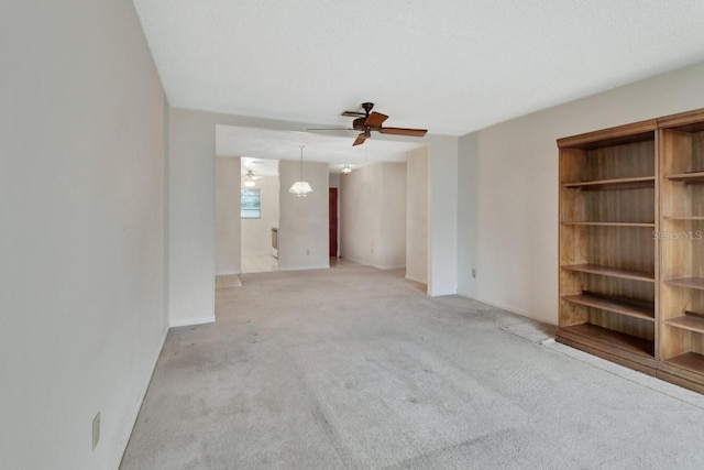 unfurnished living room with light colored carpet and ceiling fan