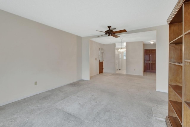 carpeted spare room with ceiling fan with notable chandelier