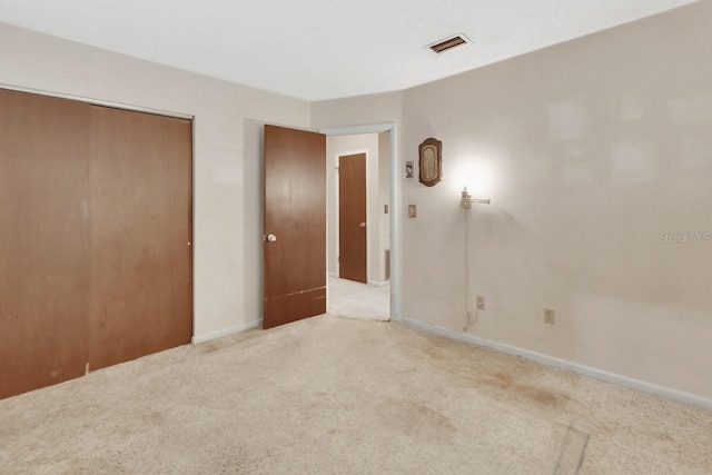 unfurnished bedroom with light carpet and a closet