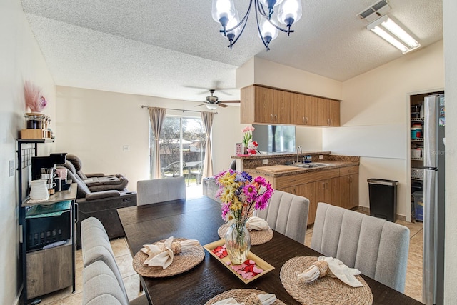 tiled dining room with lofted ceiling, sink, ceiling fan with notable chandelier, and a textured ceiling