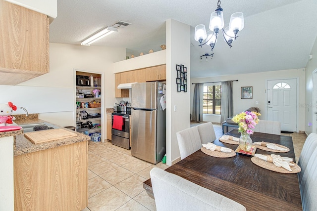 tiled dining room with an inviting chandelier, sink, vaulted ceiling, and a textured ceiling