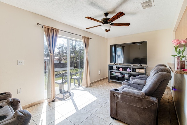 living room with ceiling fan, a textured ceiling, and light tile patterned floors