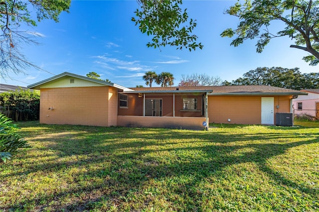 back of property with a sunroom, central AC unit, and a lawn