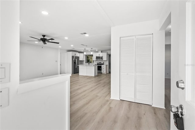 kitchen with sink, stainless steel appliances, a center island, white cabinets, and light wood-type flooring