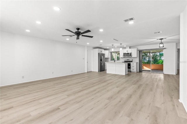 unfurnished living room featuring ceiling fan, sink, and light wood-type flooring