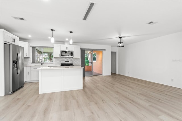 kitchen with a kitchen island, decorative light fixtures, white cabinetry, sink, and stainless steel appliances