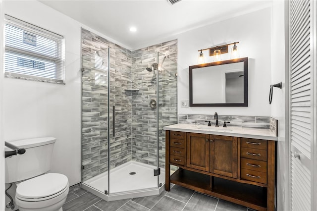 bathroom with vanity, a shower with door, and toilet