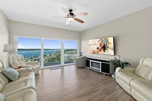 living room with hardwood / wood-style flooring, a water view, and ceiling fan