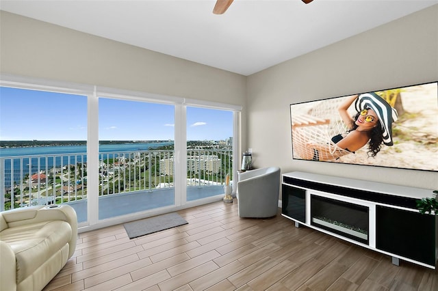 sunroom with ceiling fan and a water view