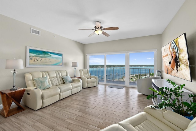 living room with a water view, ceiling fan, and light wood-type flooring