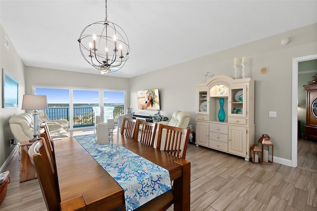 dining room featuring a water view, a chandelier, and light wood-type flooring