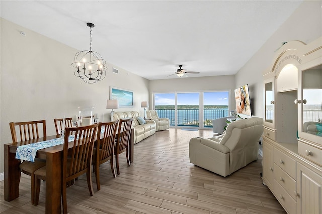 dining space with a water view and ceiling fan with notable chandelier