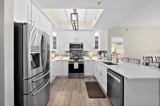 kitchen featuring appliances with stainless steel finishes, tasteful backsplash, sink, white cabinets, and a kitchen breakfast bar